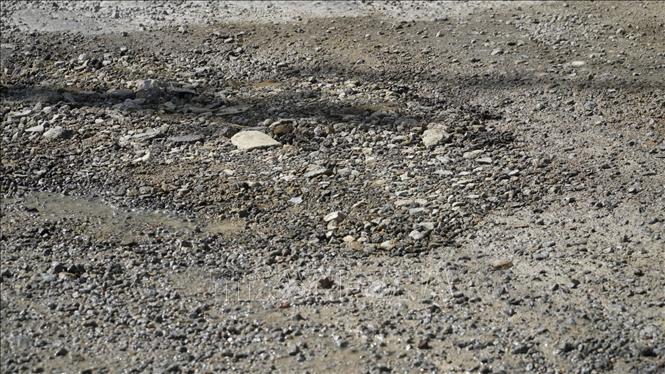 Mặt đường xuất hiện nhiều ổ gà, gây khó khăn cho các phương tiện lưu thông. Ảnh: Sỹ Thắng-TTXVN