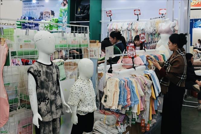 Khách tham quan mua sắm gian trưng bày thời trang quần, áo. Ảnh: Trần Việt - TTXVN 