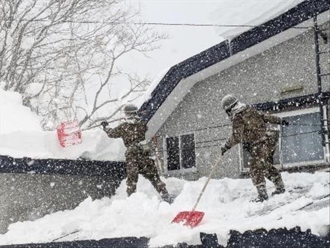 Các binh sĩ thuộc Lực lượng Phòng vệ Mặt đất Nhật Bản dọn tuyết trên mái nhà tại tỉnh Aomori. Ảnh: Kyodo/TTXVN