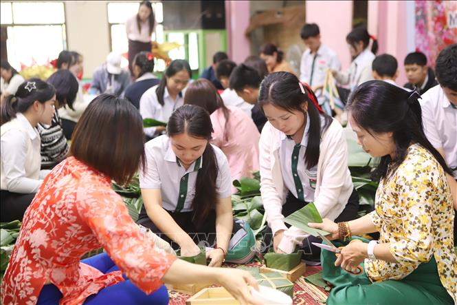 Các cô giáo hướng dẫn các em gói bánh chưng Tết. Ảnh: Xuân Tú - PV TTXVN tại Lào
