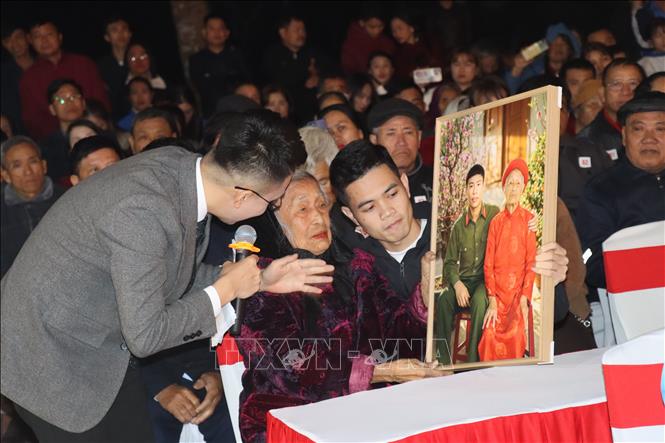 Mẹ Nguyễn Thị Phương - mẹ liệt sĩ Lê Văn Lương đón nhận bức ảnh được phục dựng người con trai cùng về đón Tết bên Mẹ. Ảnh: Hoàng Ngà - TTXVN