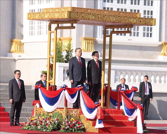 Tổng Bí thư Tô Lâm và Tổng Bí thư, Chủ tịch nước Lào Thongloun Sisoulith trên bục danh dự, thực hiện nghi lễ chào cờ. Ảnh: Thống Nhất - TTXVN
