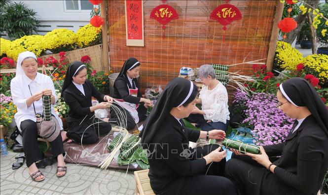 Các tình nguyện viên tôn giáo tái hiện hoạt động gói bánh tét truyền thống tại đường hoa mừng xuân Bệnh viện Chợ Rẫy. Ảnh: Đinh Hằng - TTXVN