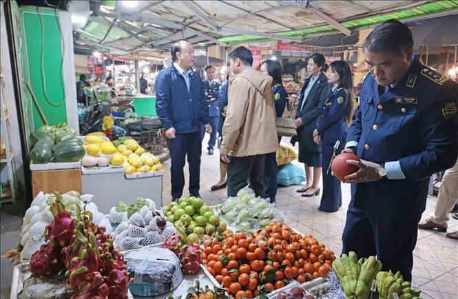Lực lượng Quản lý thị trường Hà Nội kiểm tra quầy kinh doanh tại chợ Hà Đông. Ảnh: Trần Việt - TTXVN