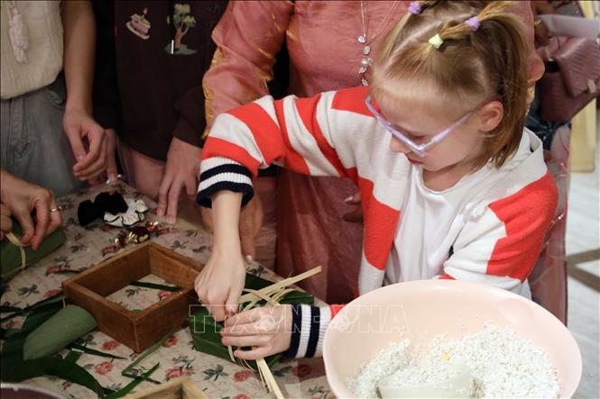 A Russian girl has a hands-on experience of making banh Chung (a Vietnamese square-shaped sticky rice cake). VNA Photo: Trần Lê Lâm