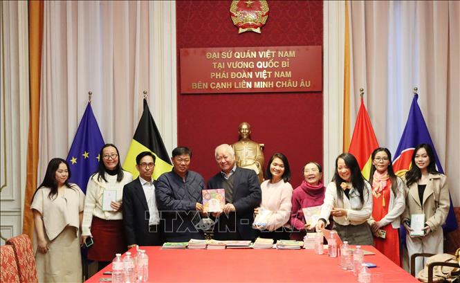 Ông Đỗ Phước Trung, Phó Giám đốc Sở Văn hóa và Thể thao Thành phố Hồ Chí Minh, trao tặng sách cho ông Huỳnh Công Mỹ, Chủ tịch Tổng hội người Việt Nam tại Vương quốc Bỉ. Ảnh: Duy Tùng - PV TTXVN tại Bỉ