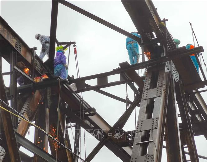 Hàng chục công nhân cùng nhiều thiết bị, vật liệu chuyên dụng tiếp tục vượt khó trong thời tiết mưa, rét của Hà Nội, khẩn trương triển khai sửa chữa, gia cố nhịp 18 cầu Long Biên. Ảnh: Thanh Tùng - TTXVN