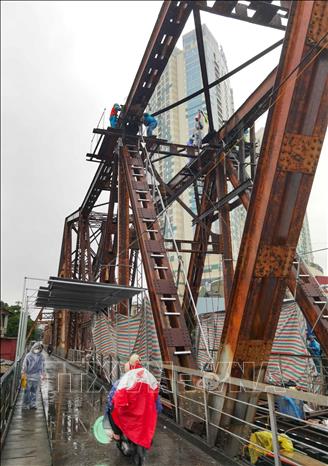 Hàng chục công nhân cùng nhiều thiết bị, vật liệu chuyên dụng tiếp tục vượt khó trong thời tiết mưa, rét của Hà Nội, khẩn trương triển khai sửa chữa, gia cố nhịp 18 cầu Long Biên. Ảnh: Thanh Tùng - TTXVN