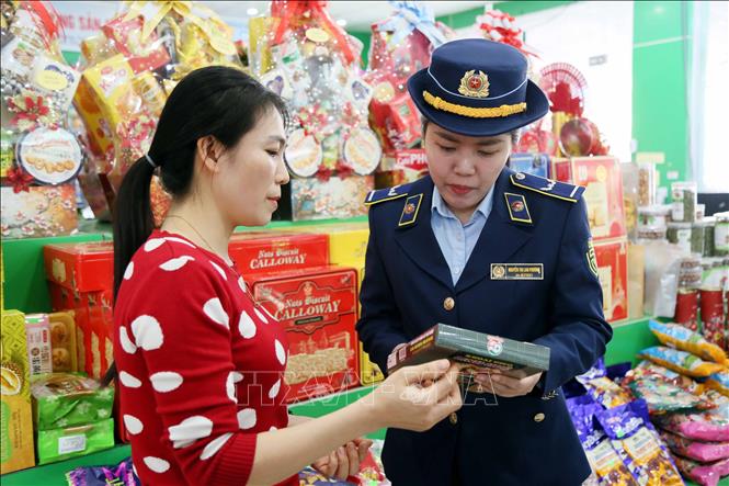 Cán bộ Chi cục QLTT Quảng Trị nhắc nhở các chủ cửa hàng niêm yết giá và bán theo giá niêm yết, chống đầu cơ, găm hàng, tăng giá bất hợp lý dịp Tết Nguyên đán. Ảnh: Tá Chuyên - TTXVN