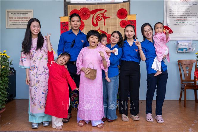Tình nguyện viên vui chơi, chụp ảnh Tết với các thiếu nhi tại Trung tâm. Ảnh: Trần Lê Lâm - TTXVN 