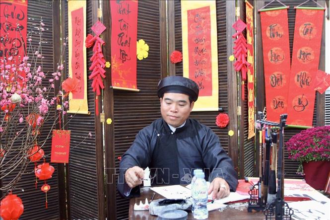 Góc Tết Việt với hình ảnh ông đồ viết thư pháp, tặng chữ bên cành đào được tái hiện. Ảnh: Quang Anh – PV TTXVN tại Campuchia. 