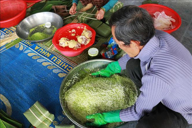 Công đoạn trộn gạo với nước cốt rau ngót để bánh có màu xanh tự nhiên. Ảnh: Tường Vi - TTXVN