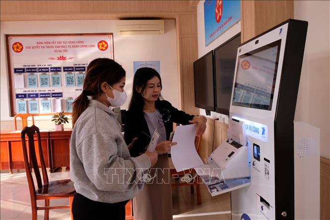 Cán bộ Trung tâm phục vụ hành chính công xã Đạ Tẻh, Lâm Đồng, hướng dẫn người dân sử dụng ki ốt tự động nhằm giảm quá tải cho cán bộ tiếp dân. Ảnh: Chu Quốc Hùng- TTXVN