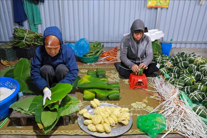 Đôi tay người thợ thoăn thoắt gói bánh, từng nếp gấp vuông vắn cho thấy sự thuần thục được tích lũy qua nhiều năm gắn bó với nghề. Ảnh: Khánh Hoà - TTXVN