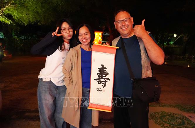 Du khách phấn khởi khi được tặng chữ thư pháp tại chương trình “Tết Hoàng cung” ở Đại Nội Huế. Ảnh: Nguyên Lý - TTXVN