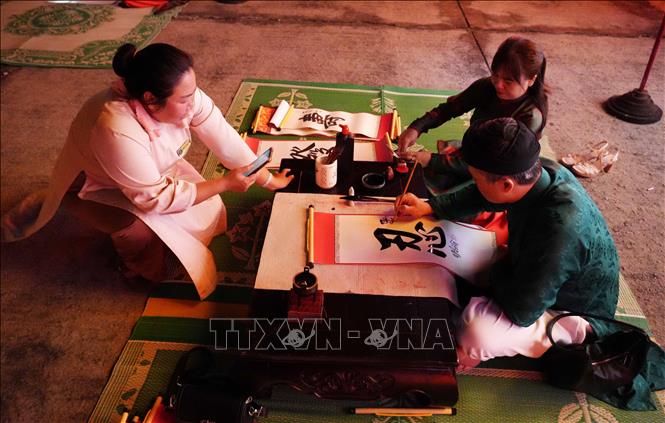 Trình diễn thư pháp tặng chữ tại Chương trình “Tết Hoàng cung” ở Đại Nội Huế. Ảnh: Nguyên Lý - TTXVN