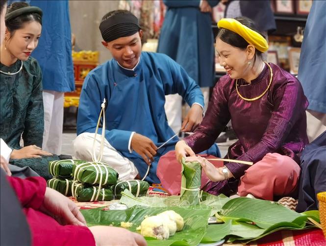 Thiếu nữ trong trang phục truyền thống gói bánh đón Tết như cách của người Hà Nội xưa. Ảnh: Thanh Tùng – TTXVN