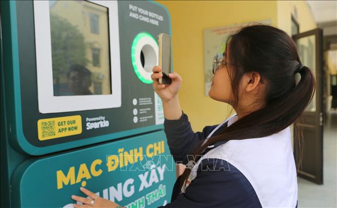 Em Phạm Diệu Triệu Vy, học sinh lớp 10 Trường THPT Mạc Đĩnh Chi quét mã QR để tích điểm tiết kiệm lượng khí thải carbon. Ảnh: Minh Thu - TTXVN
