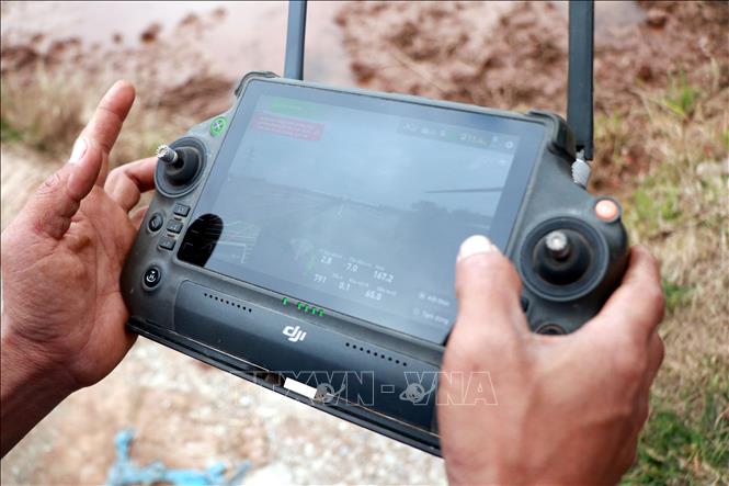 Thành viên Hợp tác xã thanh niên Nam Đại Dương (xã Nghĩa Hưng, tỉnh Ninh Bình) điều khiển thiết bị bay không người lái gieo sạ lúa. Ảnh: Nguyễn Lành - TTXVN 