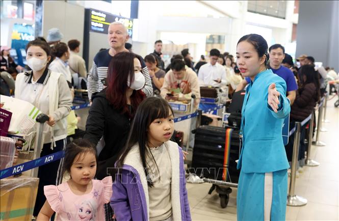 Hướng dẫn viên của hãng hàng không Vietnam Airlines hướng dẫn người dân làm thủ thục tại sân bay Nội Bài, sáng 13/2. Ảnh: Quốc Khánh - TTXVN