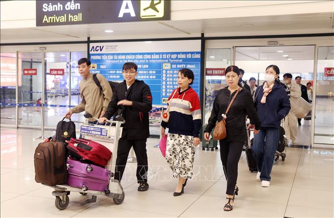 Người dân vội vã đẩy hành lý nhanh chóng rời khỏi sân bay Nội Bài, sáng 13/2. Ảnh: Quốc Khánh - TTXVN