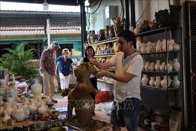 Nghệ nhân trẻ Nguyễn Viết Lâm bên hình tượng ngựa đất hấp dẫn du khách. Ảnh: Xuân Quý - TTXVN 