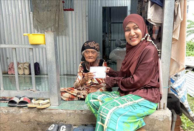 Bà Sity Hara, Phó Ban Từ thiện xã hội, Ban đại diện cộng đồng Hồi giáo tỉnh An Giang trao quà đến bà con đồng bào Chăm có hoàn cảnh khó khăn trên địa bàn nhân Tháng ăn chay Ramadan. Ảnh: Công Mạo-TTXVN