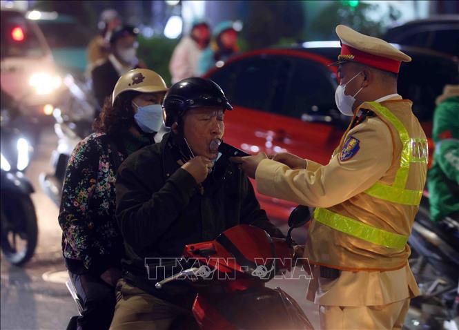 Cán bộ, chiến sĩ đội CSGT số 3 kiểm tra đồng nồng độ cồn của người tham gia giao thông tại tuyến đường Láng - Nguyễn Chí Thanh, tối 13/2. Ảnh: Phạm Kiên - TTXVN