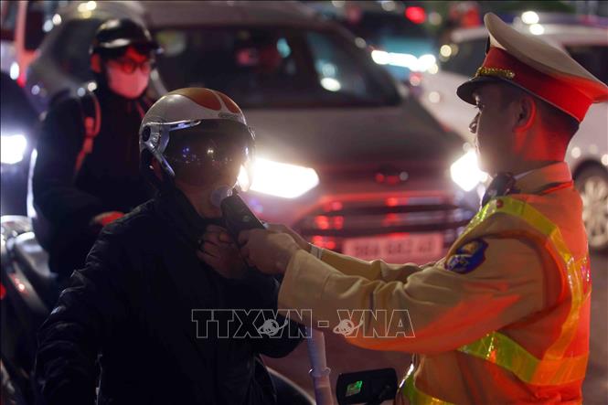 Cán bộ, chiến sĩ đội CSGT số 3 kiểm tra đồng nồng độ cồn của người tham gia giao thông tại tuyến đường Láng - Nguyễn Chí Thanh, tối 13/2. Ảnh: Phạm Kiên - TTXVN