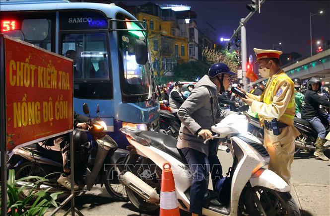 Cán bộ, chiến sĩ đội CSGT số 3 kiểm tra đồng nồng độ cồn với người tham gia giao thông tại tuyến đường Láng - Nguyễn Chí Thanh, tối 13/2. Ảnh: Phạm Kiên - TTXVN