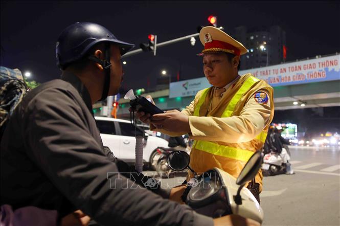 Cán bộ, chiến sĩ đội CSGT số 3 kiểm tra đồng nồng độ cồn của người tham gia giao thông, tối 13/2. Ảnh: Phạm Kiên - TTXVN