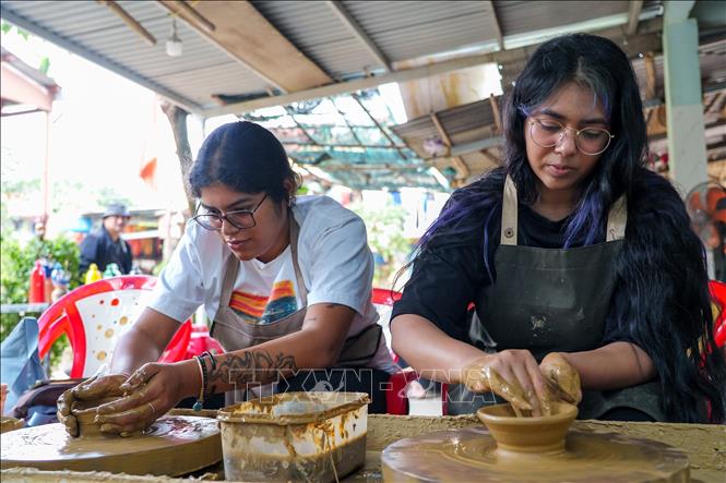 International tourists are eager to try their hand at decorating raw pottery. VNA Photo: Khoa Chương