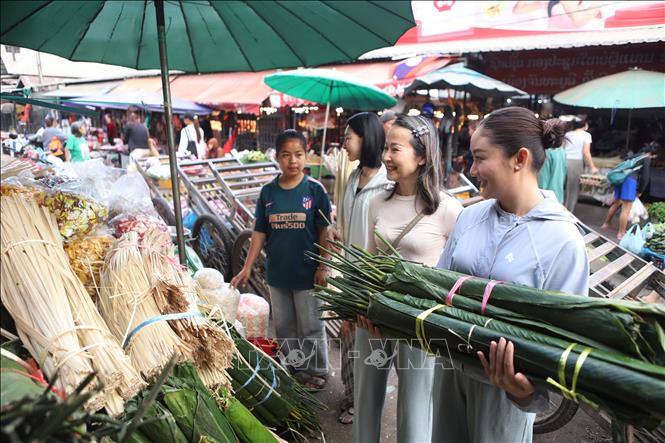 Chị Phạm Thu Hương, 56 tuổi, Việt kiều tại Lào, hướng dẫn các con cách chọn lá dong gói bánh chưng. Ảnh: Xuân Tú - PV TTXVN tại Lào