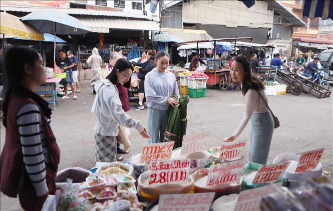 Chị Phạm Thu Hương, 56 tuổi, Việt kiều tại Lào, hướng dẫn các con cách chọn gạo nếp. Ảnh: Xuân Tú - PV TTXVN tại Lào