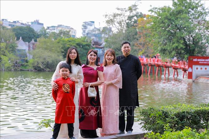 Người dân chụp ảnh lưu lại khoảnh khắc Xuân rực rỡ tại khu vực xung quanh Hồ Hoàn Kiếm. Ảnh: Khánh Hoà - TTXVN