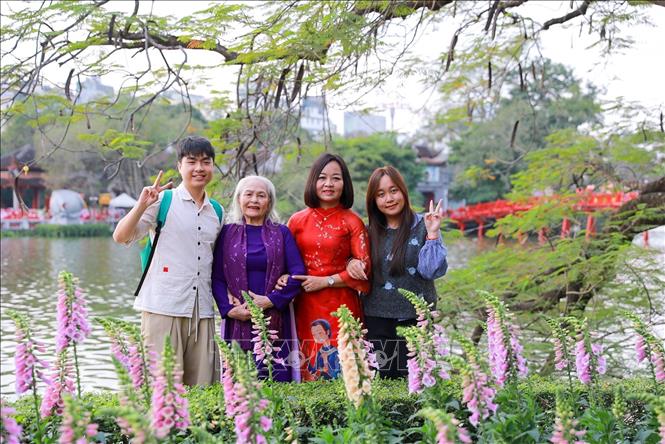 Người dân chụp ảnh lưu lại khoảnh khắc Xuân rực rỡ tại khu vực xung quanh Hồ Hoàn Kiếm. Ảnh: Khánh Hoà - TTXVN