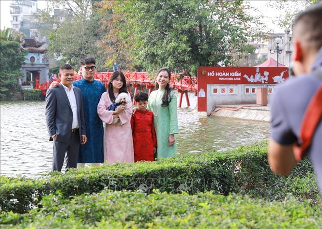 Người dân chụp ảnh lưu lại khoảnh khắc Xuân rực rỡ tại khu vực xung quanh Hồ Hoàn Kiếm. Ảnh: Khánh Hoà - TTXVN