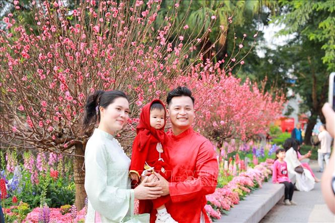 Người dân chụp ảnh lưu lại khoảnh khắc Xuân rực rỡ tại khu vực xung quanh Hồ Hoàn Kiếm. Ảnh: Khánh Hoà - TTXVN