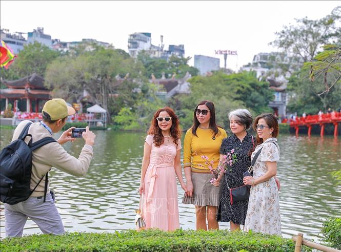 Người dân chụp ảnh lưu lại khoảnh khắc Xuân rực rỡ tại khu vực xung quanh Hồ Hoàn Kiếm. Ảnh: Khánh Hoà - TTXVN