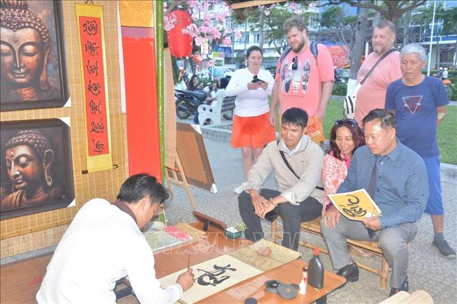 Du khách thích thú trải nghiệm không gian thư pháp tại triển lãm ảnh “Sắc Xuân Đất nước”. Ảnh: TTXVN phát