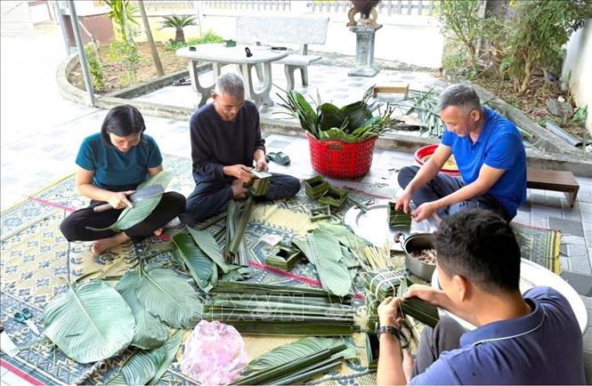 Gói bánh chưng bằng khuôn lá dừa đòi hỏi nhiều công đoạn, cần nhiều thời gian nên có sự tham gia của nhiều thành viên trong gia đình. Ảnh: TTXVN phát 
