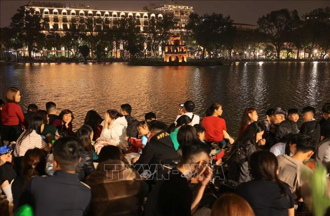 Rất đông người dân ngồi xung quanh Hồ Hoàn Kiếm chờ xem màn pháo hoa chào đón năm mới Bính Ngọ. Ảnh: Hoàng Hiếu - TTXVN