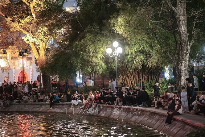 Rất đông người dân ngồi xung quanh Hồ Hoàn Kiếm chờ xem màn pháo hoa chào đón năm mới Bính Ngọ. Ảnh: Hoàng Hiếu - TTXVN