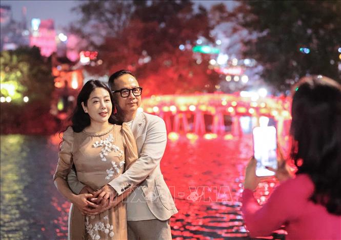 Người dân lưu giữ kỷ niệm bên cầu Thê Húc trong thời khắc đón chờ năm mới Bính Ngọ. Ảnh: Hoàng Hiếu - TTXVN