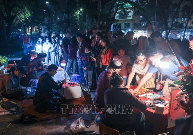 Các ông đồ ngồi cho chữ đầu xuân thu hút đông đảo người dân xếp hàng xin chữ, ước nguyện về bình an, tài lộc và thành công trong năm mới. Ảnh: Hoàng Hiếu - TTXVN