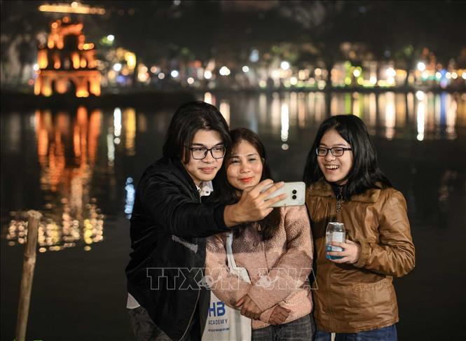Người dân chụp ảnh kỷ niệm trong thời khắc đón năm mới Bính Ngọ bên hồ Hoàn Kiếm. Ảnh: Hoàng Hiếu - TTXVN