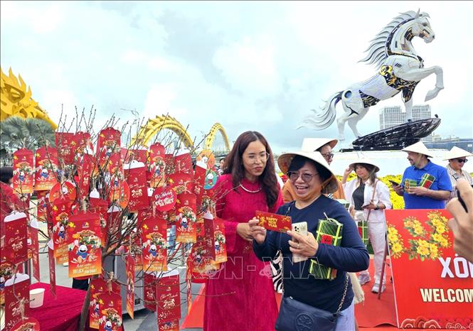 Du khách quốc tế được tặng quà lì xì đầu năm. Ảnh: Trần Lê Lâm - TTXVN 