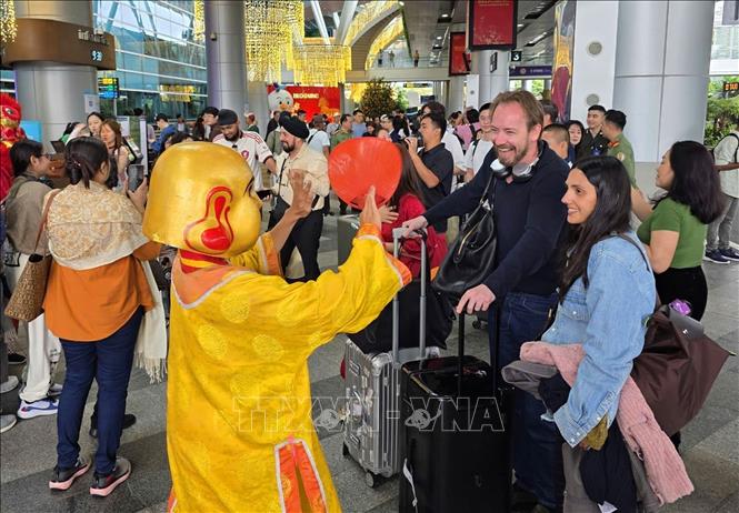 Khách du lịch quốc tế thích thú khi vừa đến Sân bay quốc tế Đà Nẵng được chào bởi các màn biểu diễn nghệ thuật trong ngày mùng 1 Tết. Ảnh: Trần Lê Lâm - TTXVN 