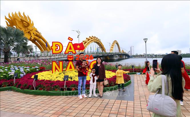 Nhiều gia đình diện áo dài truyền thống cùng dạo chơi, chụp ảnh lưu lại khoảnh khắc bên đường hoa Xuân và các tiểu cảnh trang trí Tết rực rỡ. Ảnh: Trần Lê Lâm - TTXVN 