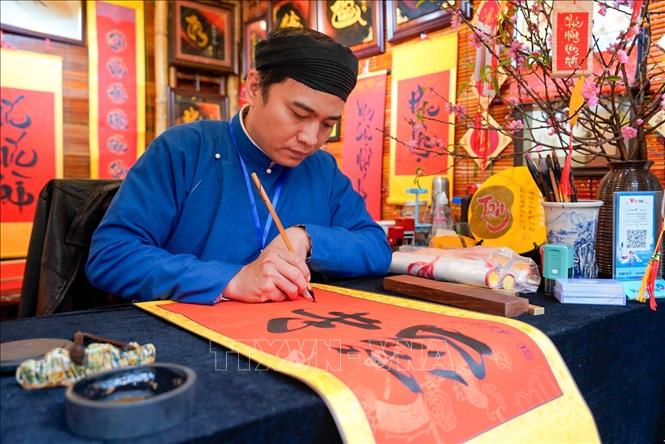 Cứ mỗi độ Xuân về, hình ảnh ông đồ bày mực tàu giấy đỏ lại trở nên quen thuộc, mang theo những con chữ gửi gắm lời chúc phúc, may mắn và tài lộc. Ảnh: Khánh Hoà - TTXVN